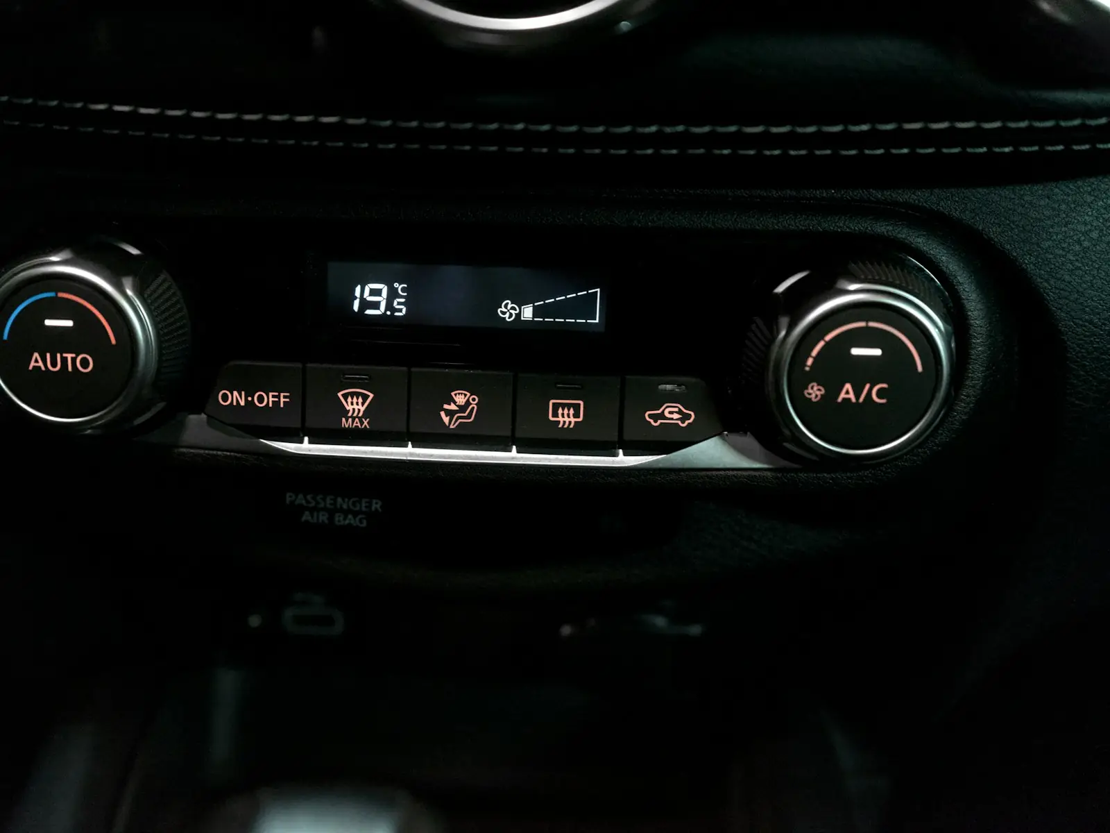 A car's climate control panel with the A/C button