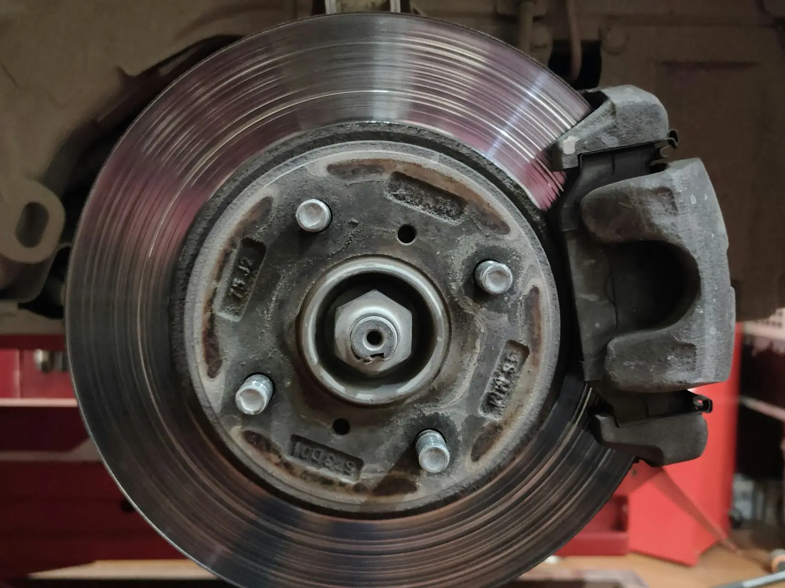 A worn brake rotor and caliper on a car with the wheel off