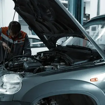 A mechanic works under the open hood of an SUV in the shop