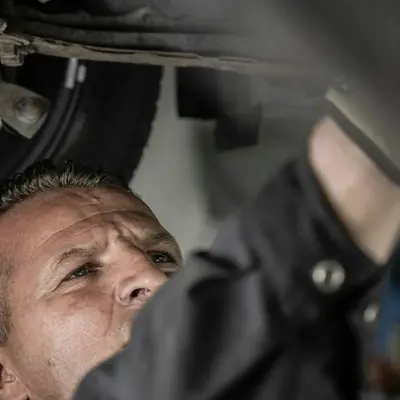 A mechanic checks the suspension from under the car